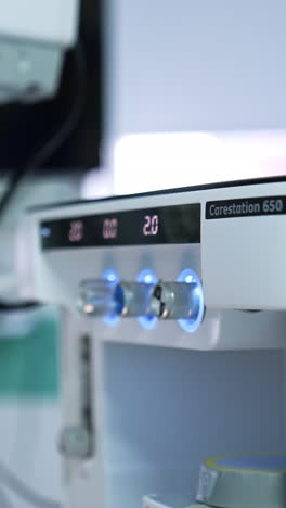 male hand of a doctor choosing the parameters on the touch screen of equipment. anesthesia delivery system at foreground. blurred backdrop. vertical video