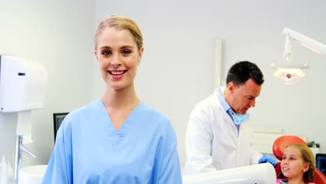 Portrait-of-smiling-nurse-standing-in-clinic