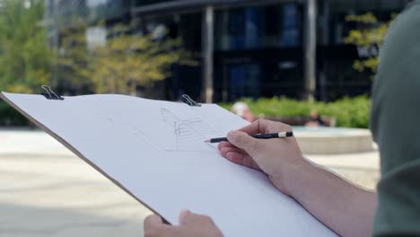 unrecognizable person sketching a building exterior