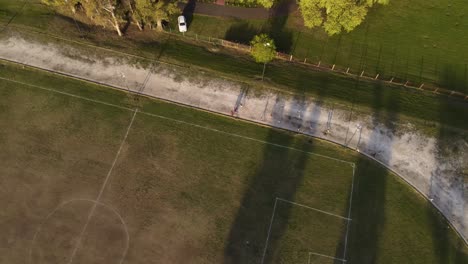 aerial top down view of children running and training at sunset in a football court