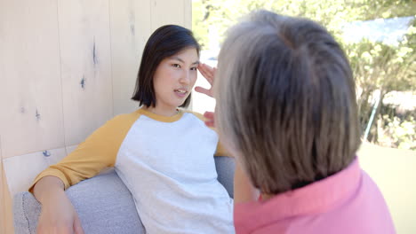talking with senior, young asian woman sitting on couch, engaging in conversation