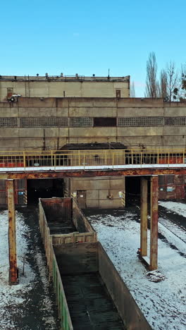 a row with containers on the railway line stand at the entrance to the tunnel on the background other rows in the terminal station in the winter season. aerial view. vertical video