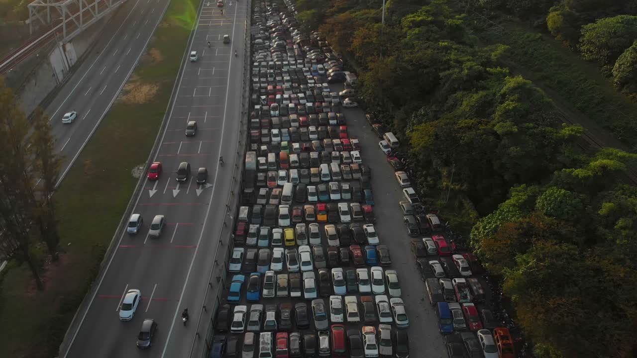Luftaufnahme von verlassenen Autos auf einem Schrottplatz mit Autobahnverkehr bei Sonnenaufgang in Kuala Lumpur, Malaysia.