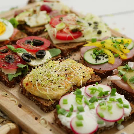 Tasty--homemade-small-sandwiches-with-various-ingredients-served-on-wooden-chopping-board