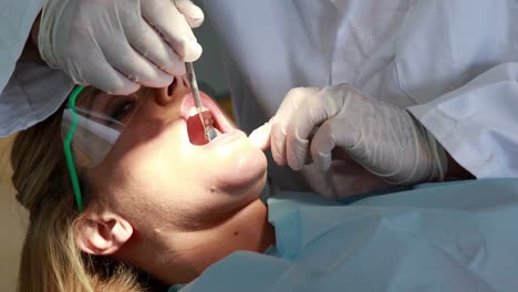 dentista examinando los dientes de un paciente bajo una luz brillante.