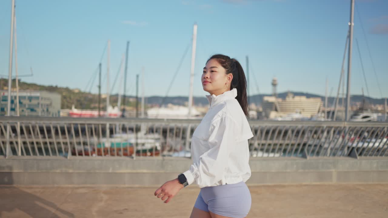 晴れた日に港のそばを歩いている若いアジア人女性。