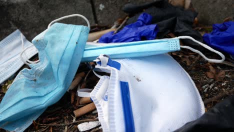 mascarillas desechables sucias para el virus de la corona y guantes de látex entre la basura de los cigarrillos en la acera de la calle empujando hacia adentro