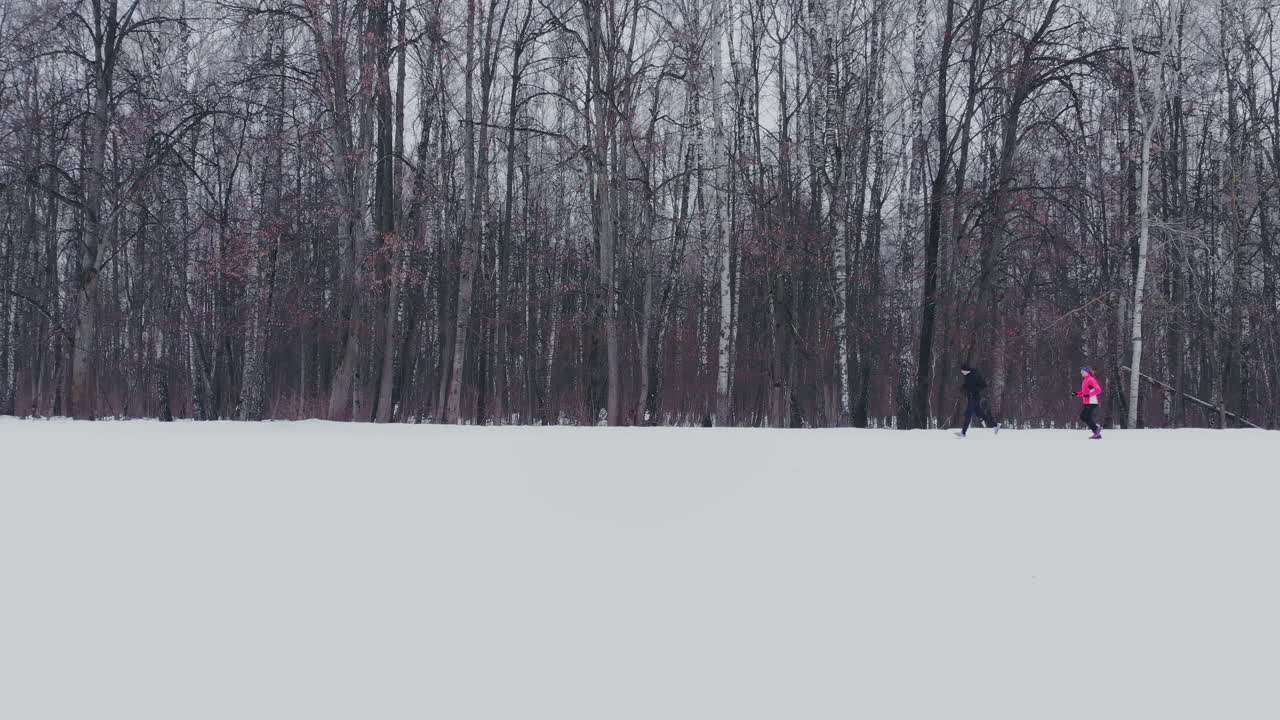 한 남자와 한 여자가 겨울 훈련과 건강 관리를 통해 숲 속을 달리고 있습니다. 아침 조깅, 건강한 생활 방식. 공중선