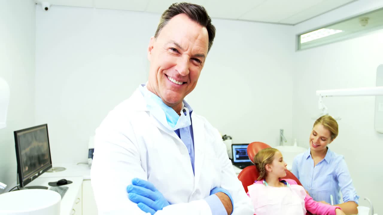 Smiling dentist standing with arms crossed at dental clinic