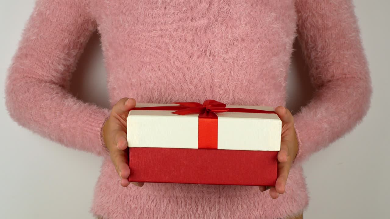 크리스마스를 축하하는 선물을 들고 있는 여성의 손. 놀라운 활을 가진 밝은 상자에 새해와 크리스마스 선물. 선물 상자의 클로즈업의 4k 비디오.
