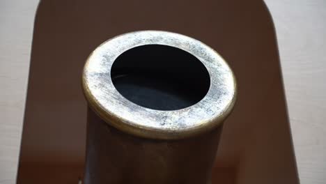 Close-up-of-the-objective-lens-of-an-antique-telescope-used-in-a-museum-to-view-paintings