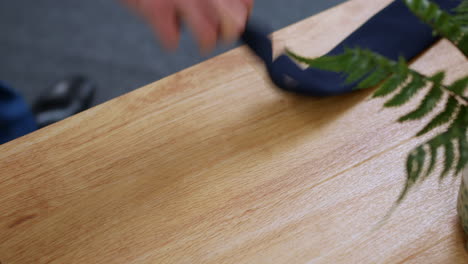 a man picking up a clip on tie from a table desk at work