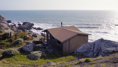 cabaña de madera en punto rocoso, campamento ambiental de barranco empinado en stinson beach, estados unidos