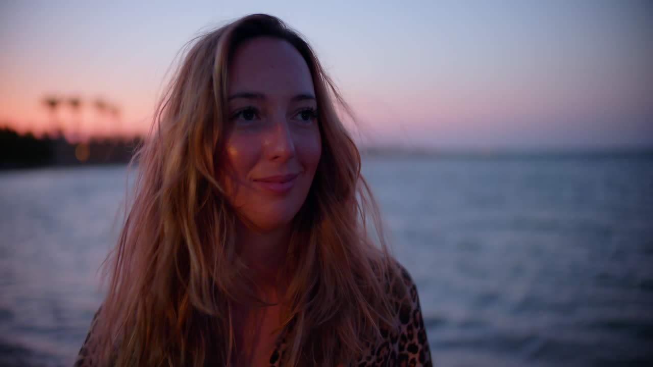 Closeup of a beautiful young woman on the windy beach at sunset