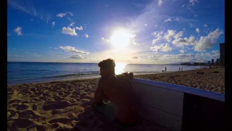 Surfer-with-a-surfboard-sitting-on-the-beach-4k