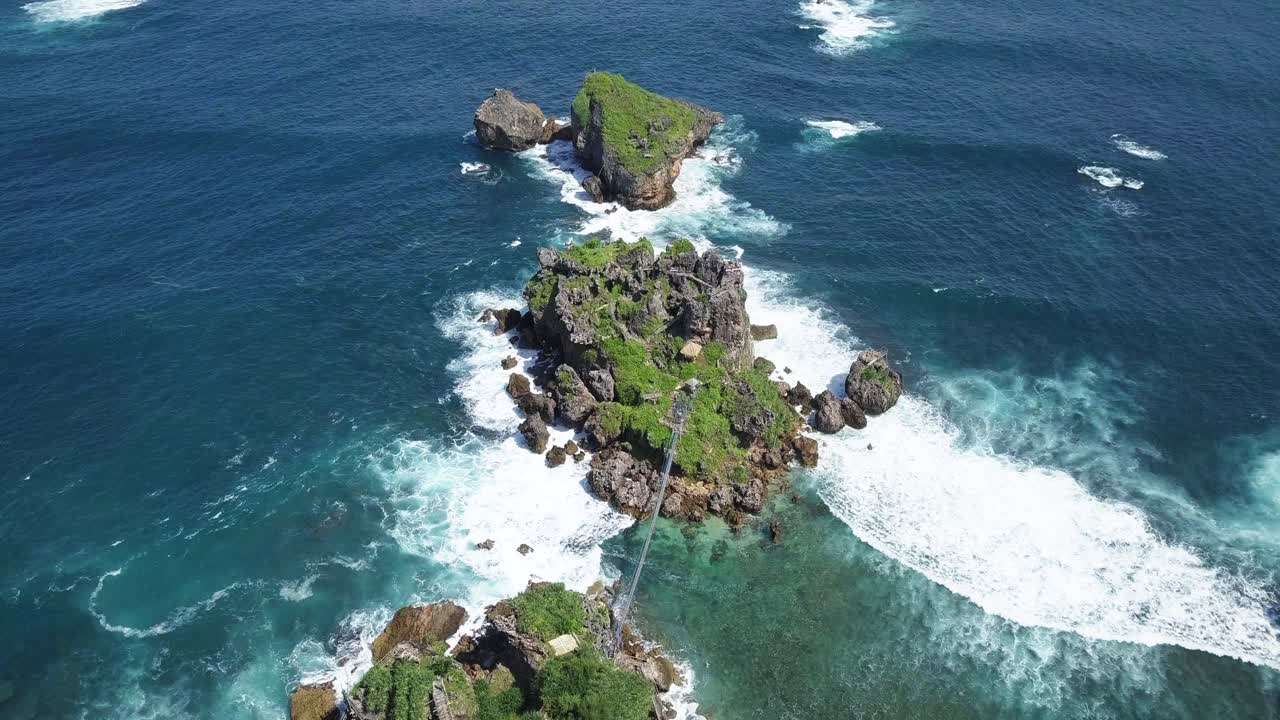 vista aérea de rocas cubiertas de maleza en el océano, golpeadas por olas durante el día soleado - isla de timang, yogyakarta, indonesia