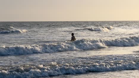 Junger-Mann-Spielt-Bei-Sonnenuntergang-Mit-Den-Wellen-Im-Meer