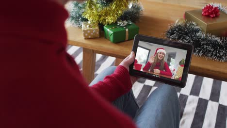 Hombre-Caucásico-Saludando-Y-Usando-Una-Tableta-Para-Una-Videollamada-Navideña-Con-Una-Mujer-Sonriente-En-La-Pantalla