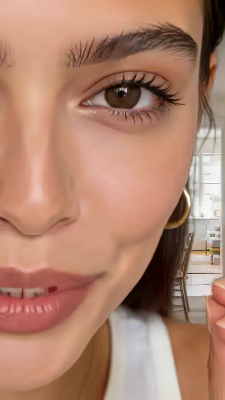 Vertical video: Talking woman white tank gold hoops as camera starts speaking to camera in kitchen