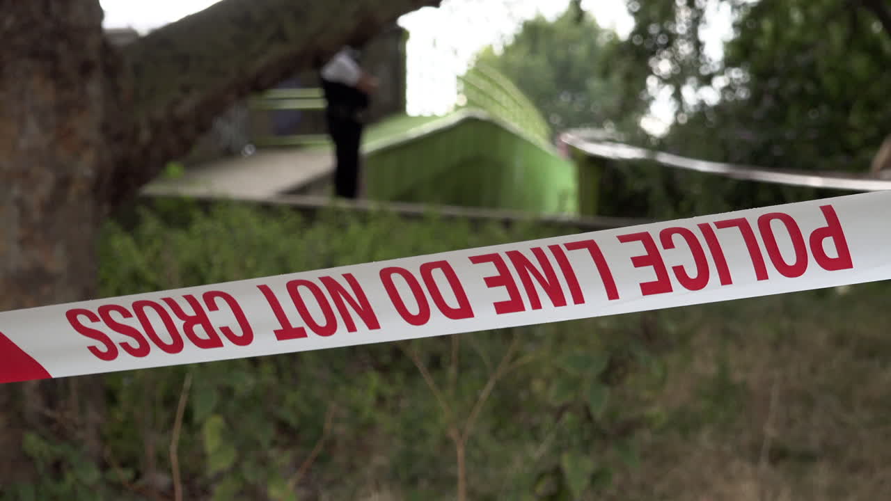 A London Metropolitan police officer stands guard at a taped off police cordon of a gun and knife crime scene