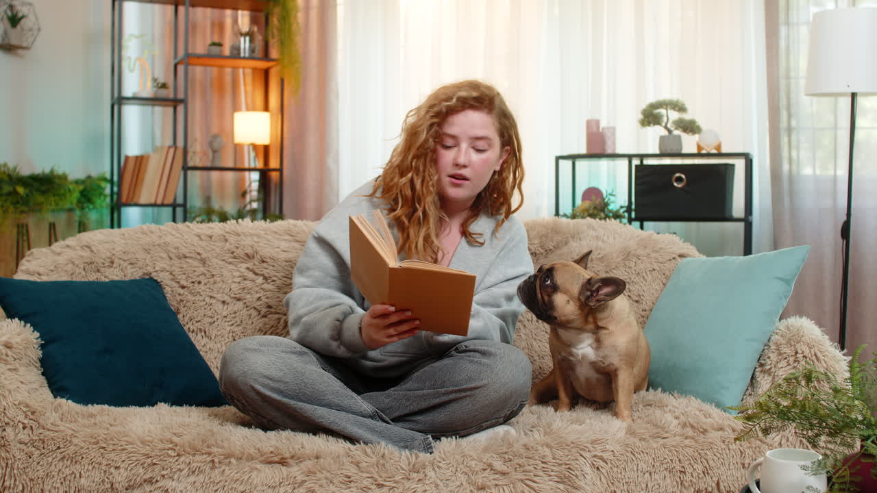 Young woman reading bedtime story to pug dog on home sofa peaceful end of day with emotional care