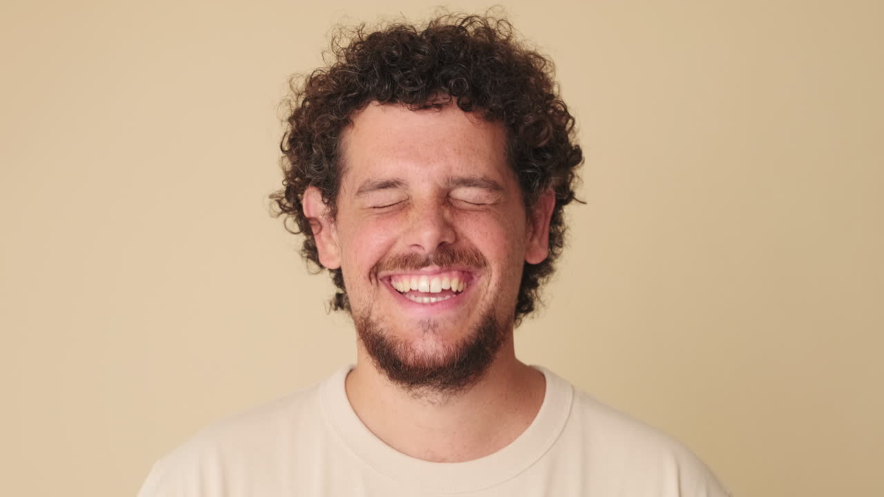 Ritratto di un uomo felice con capelli ricci e barba che ride