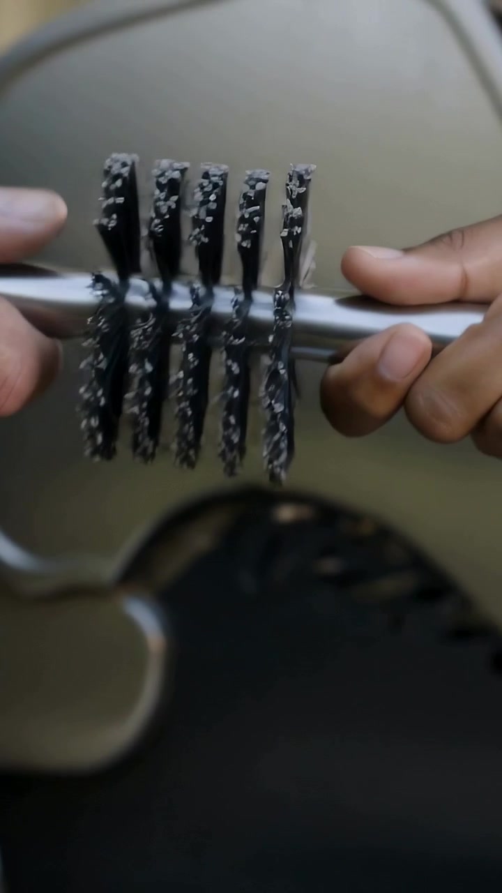 Video verticale: Una mano inserisce una spazzola metallica rotante, posizionandola sul vassoio raccogligocce della griglia dopo averla ispezionata.