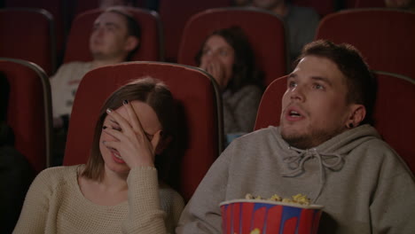 personas viendo películas de miedo en el cine. joven rociando palomitas de maíz