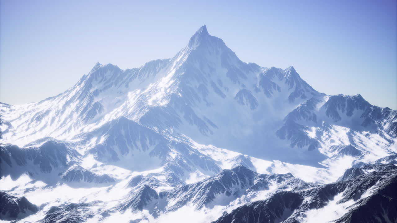 el pico de la montaña cubierto de nieve se eleva dramáticamente contra el cielo azul claro
