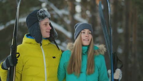 Active-senior-couple-on-skis-moving-down-snowdrift-in-snowfall-during-training-in-winter-forest