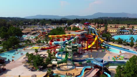 Umlaufende-Drohnenaufnahme-Eines-Belebten-Wasserparks-An-Einem-Sonnigen-Sommertag