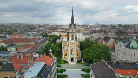 4k aerial shot approaching st. francis of assisi parish, a neo-romanesque catholic church in budapest, hungary, under an overcast sky.