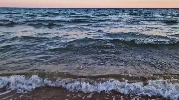 Спокойные морские волны мягко накатывают на испанское побережье на закате, идеально подходит для тем путешествий и отдыха.