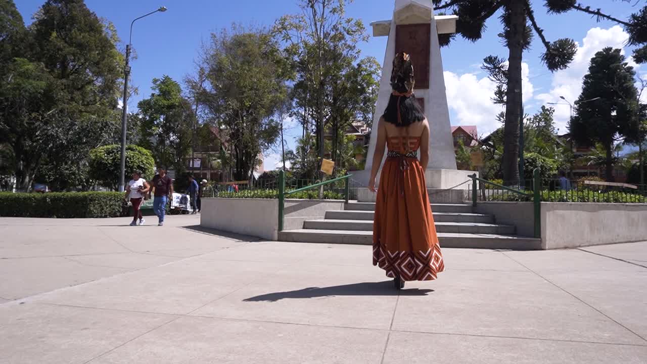 A young woman wearing a traditional costume from Oxapampa, Peru, is walking in the Plaza de Armas park in Oxapampa, Peru.