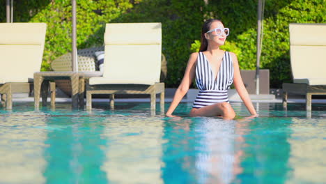 Bella-Modelo-Femenina-En-Traje-De-Baño-Sentada-En-La-Piscina-De-Un-Complejo-Tropical-De-Lujo