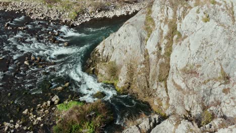 whitewater rapids flowing through rocky mountain canyon, aerial view