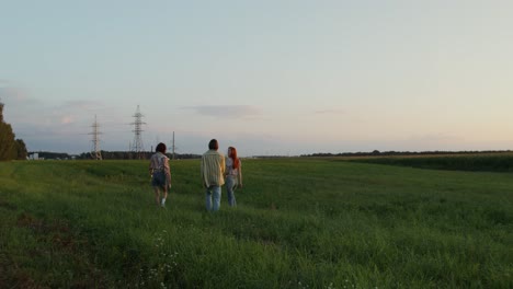 people walking in a field at sunset