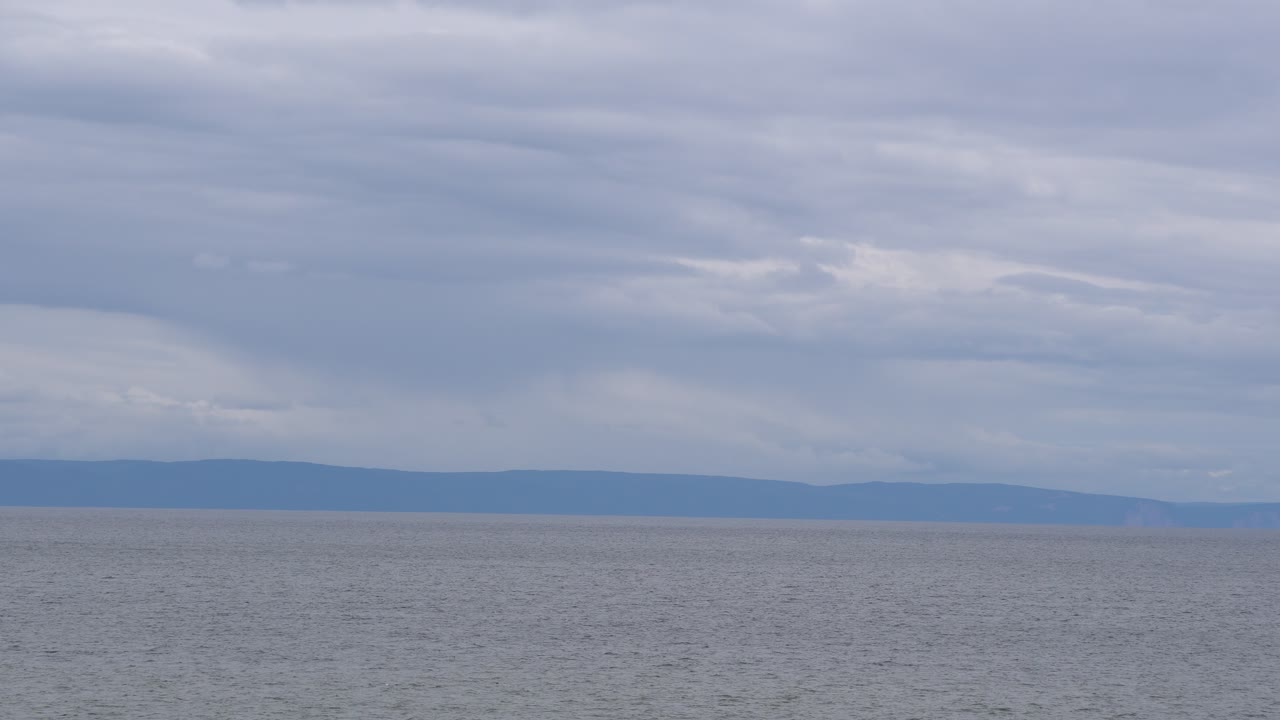 выдающийся вид на берег моря с горами позади в серый пасмурный день