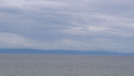 an outstanding view of the seashore with mountains behind under a gray cloudy day