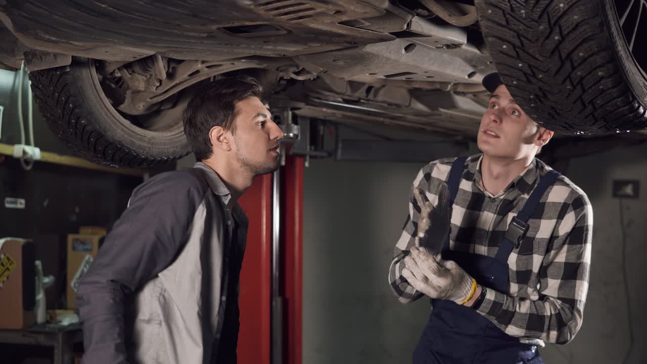 un guapo técnico de reparación automotriz mostrando a su cliente los principales problemas del coche.