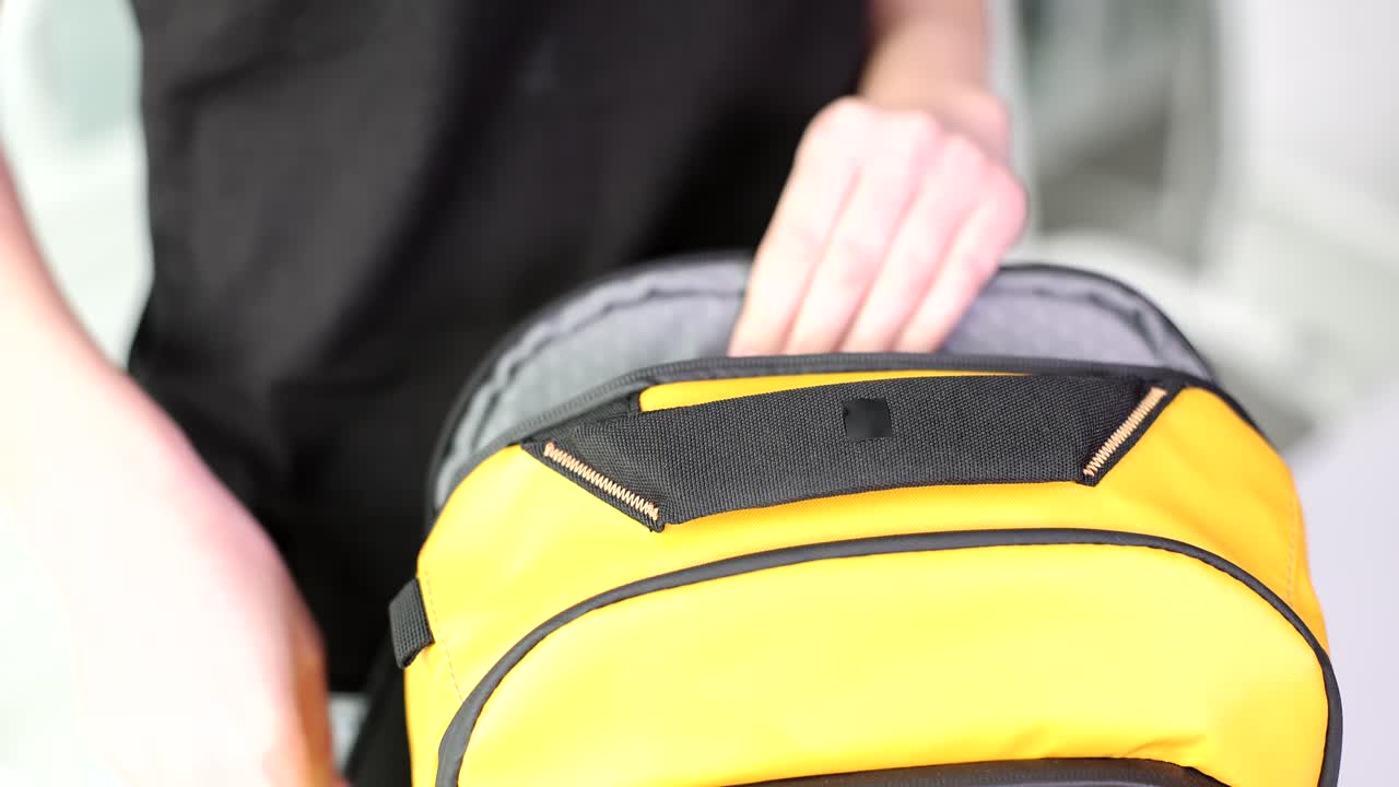 Person putting a laptop in a yellow backpack
