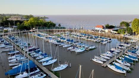 aerial dolly in of sailboats tied up inline in olivos port leading to de la plata river at sunset, buenos aires