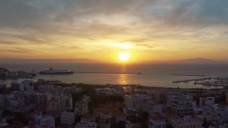 aerial drone flight over downtown mitilini revealing golden sunrise at sea with ferry to athens, lesvos, greece