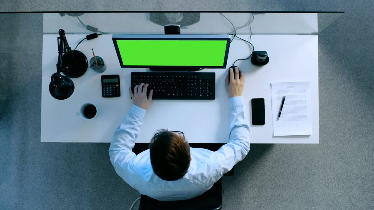 vista superior de un diligente contador trabajando en su escritorio en una computadora personal con pantalla verde encendida. también firmó papeles y teléfono inteligente sobre su mesa.