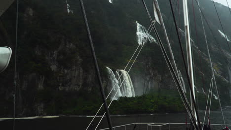 falls cascade down steep slope of milford sound on rainy day