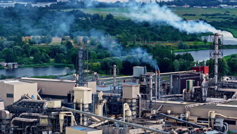 drone shot capturing hazardous smoke emitting out of chimneys of an industry during daytime