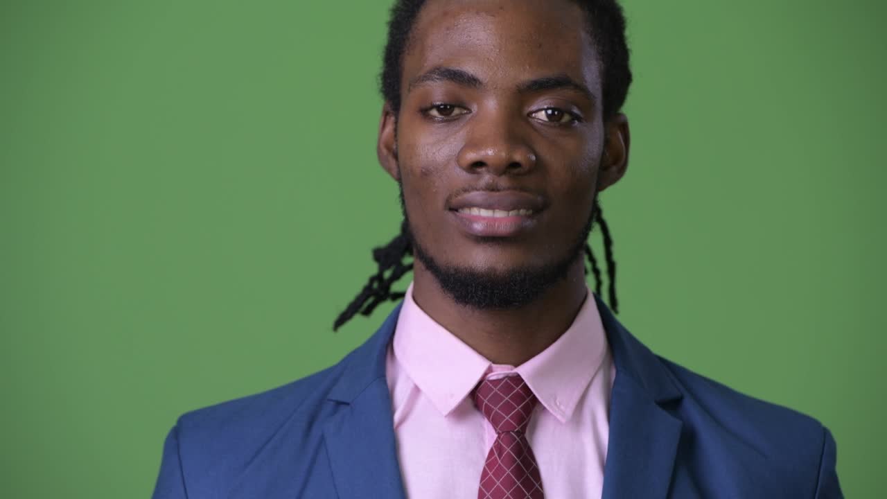 joven empresario africano guapo con dreadlocks contra un fondo verde