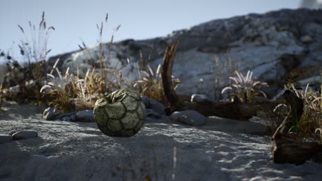 una vieja pelota de fútbol rota arrojada yace en la arena de la playa del mar
