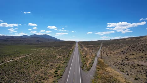 Long-straight-Open-road-in-Nevada-Desert-with-two-cars-passing-each-other---Aerial-ascending