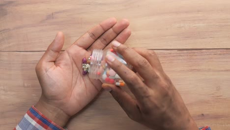 person holding a container of pills over a wooden table